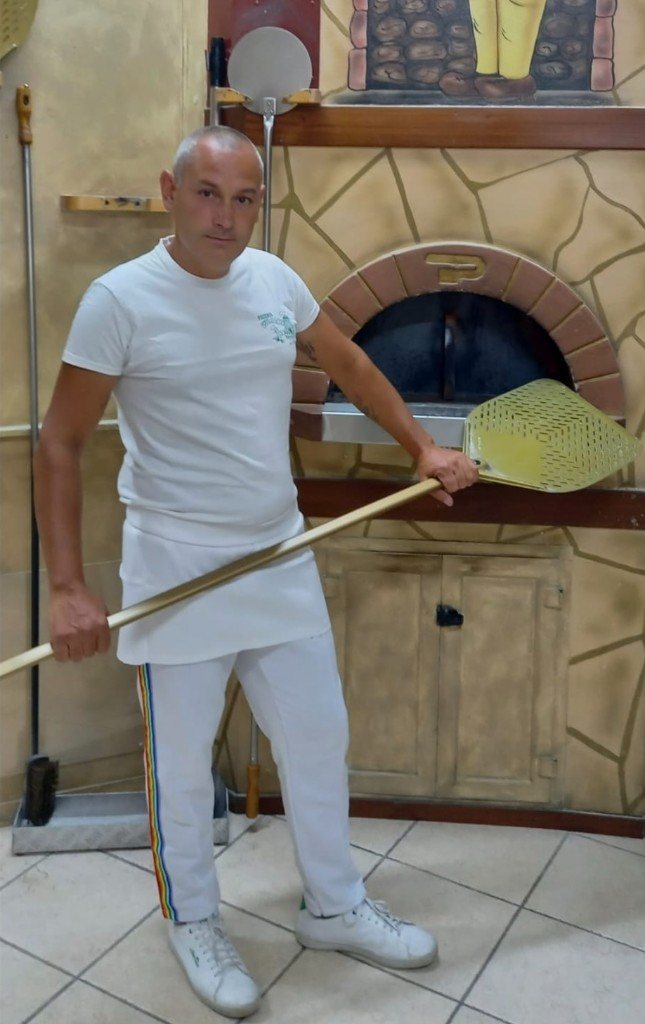 Francesco al lavoro davanti al forno a legna, con la pala.